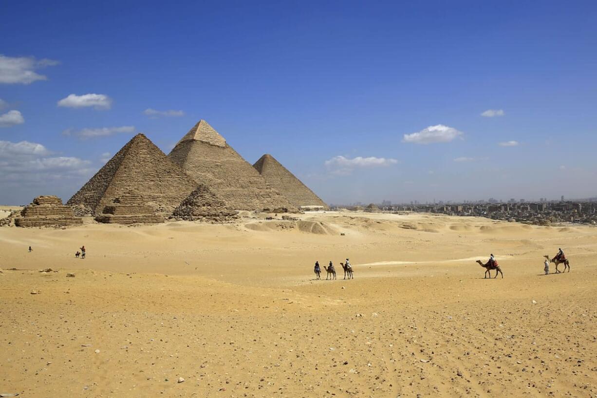 Turists ride camels at the historical site of the Giza Pyramids in Giza, near Cairo, Egypt. Republican presidential candidate Ben Carson says it?s still his belief the great pyramids Egypt were built by the Biblical figure Joseph to store grain, and not as tombs for pharaohs.