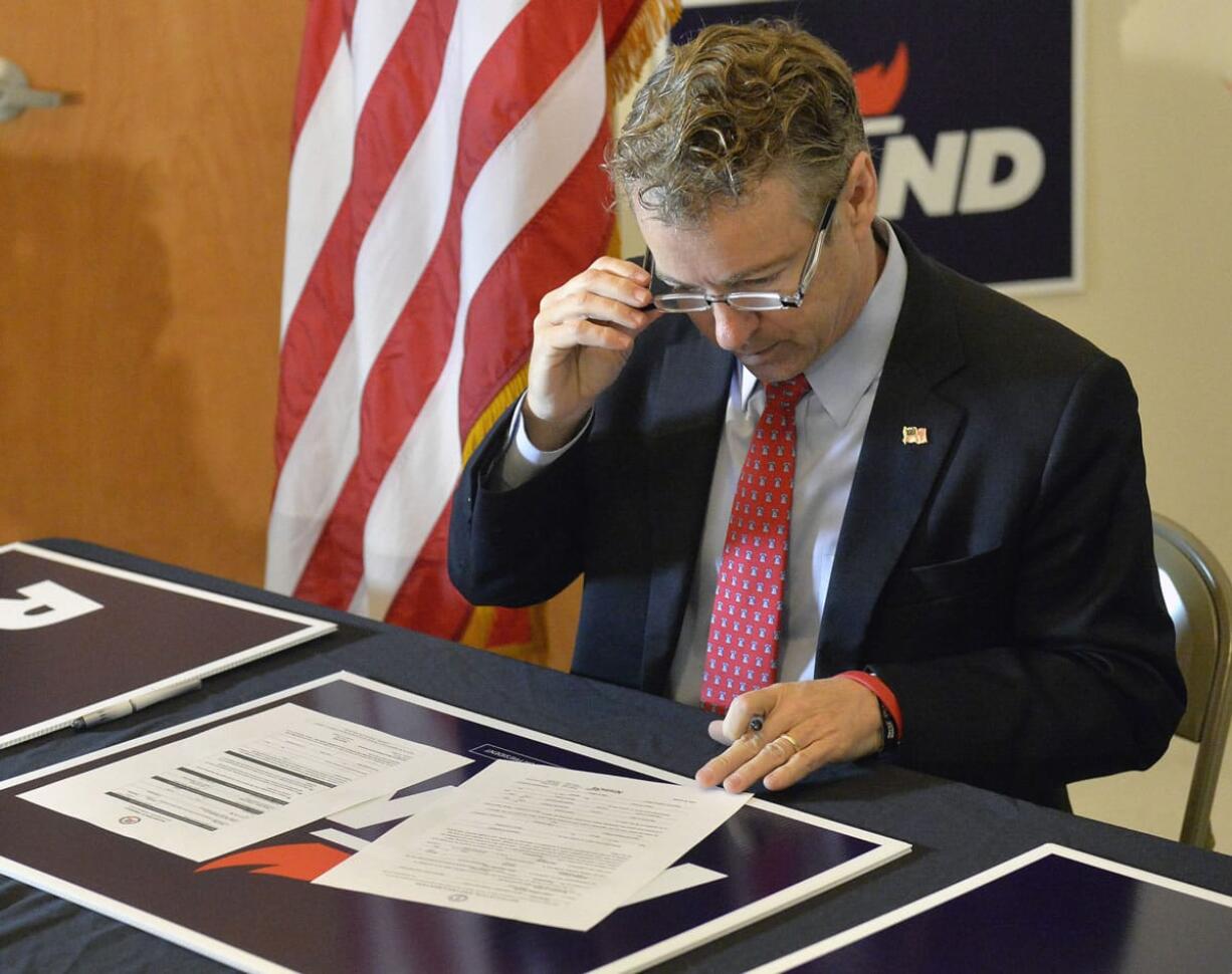 Republican presidential candidate, Sen. Rand Paul, R-Ky., looks over the forms he is to sign to officially file for his re-election to the Senate and for the office of president Monday in Louisville, Ky. (AP Photo/Timothy D.