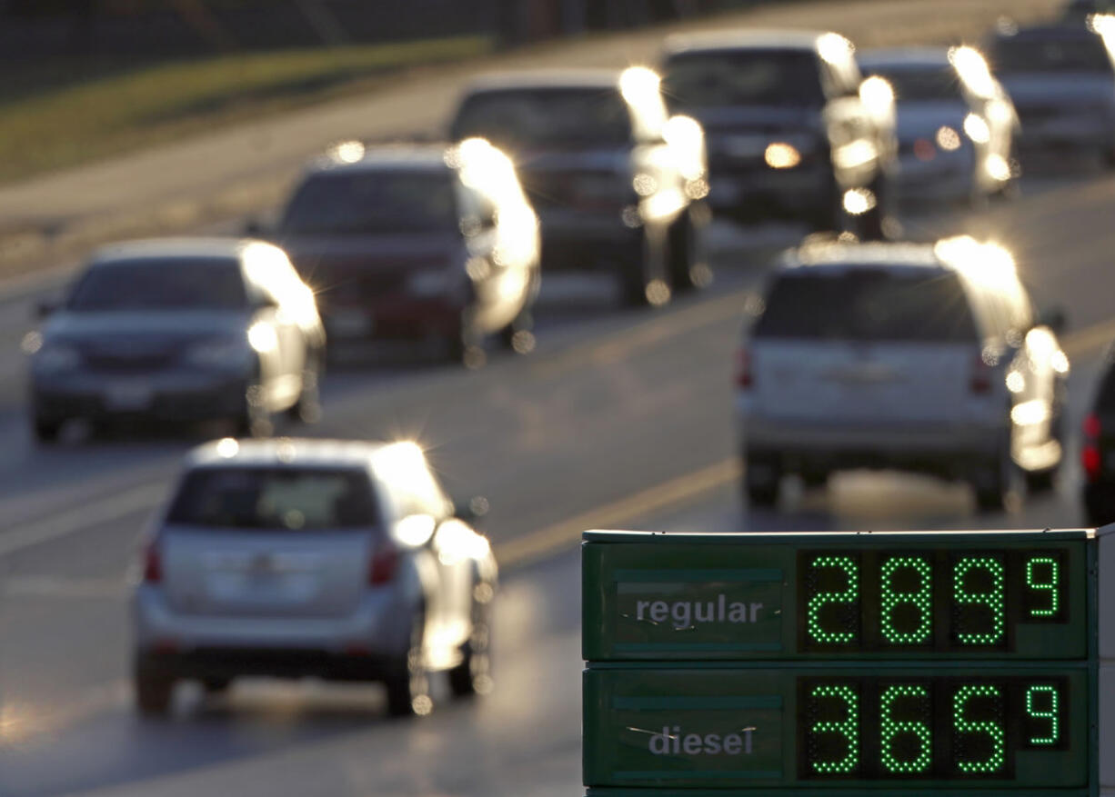 Motorists drive past a gas station selling regular unleaded gasoline for less than $3.00 a gallon, in Independence, Mo.