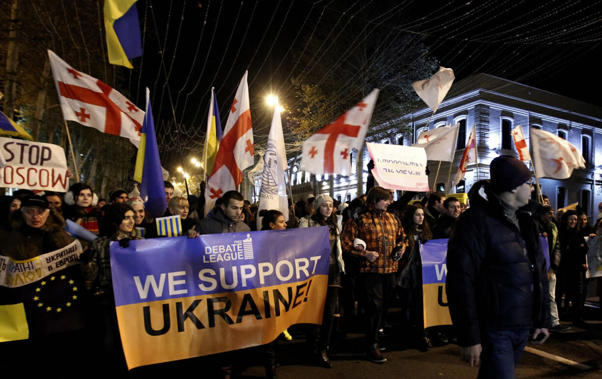 Demonstrators carry posters and Georgian and Ukrainian flags as they head to a rally in support of the Ukrainian opposition in downtown Tbilisi, Georgia, on Wednesday.