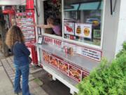 McKinze Cook, co-owner of Portland food cart Kargi Gogo, shows a customer the Georgian food cart's menu on Tuesday in Portland.