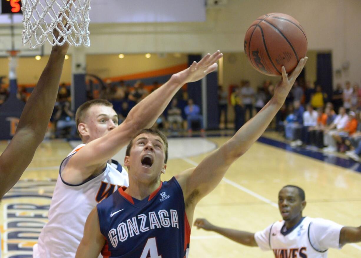 Gonzaga guard Kevin Pangos, center, puts up a shot as Pepperdine forward David Jesperson defends during the first half of an NCAA college basketball game, Thursday, Jan. 16, 2014, in Malibu, Calif. (AP Photo/Mark J.