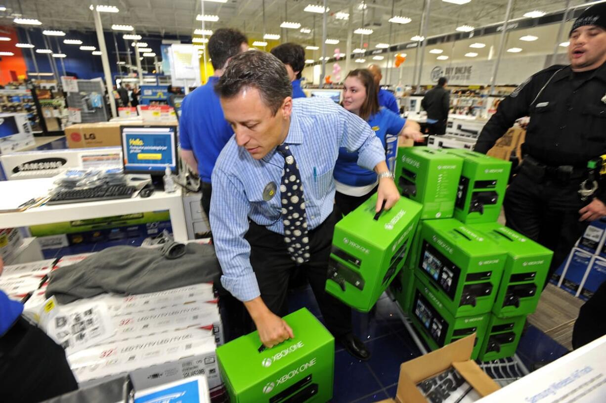 Peter Schultz helps stack a pallet of Xbox One game sets for a doorbuster sale at a Best Buy store just before midnight on Thanksgiving Day on Thursday in Dunwoody, Ga.