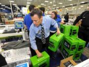 Peter Schultz helps stack a pallet of Xbox One game sets for a doorbuster sale at a Best Buy store just before midnight on Thanksgiving Day on Thursday in Dunwoody, Ga.