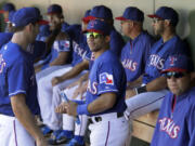 Seattle Seahawks quarterback Russell Wilson, center, talks with Texas Rangers' Adam Rosales, left, as he stands in the dugout during a spring training game against the Cleveland Indians on Monday in Surprise , Ariz.