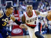 Portland Trail Blazers guard Damian Lillard, right, drives on Utah Jazz guard Trey Burke during the first half  Friday.