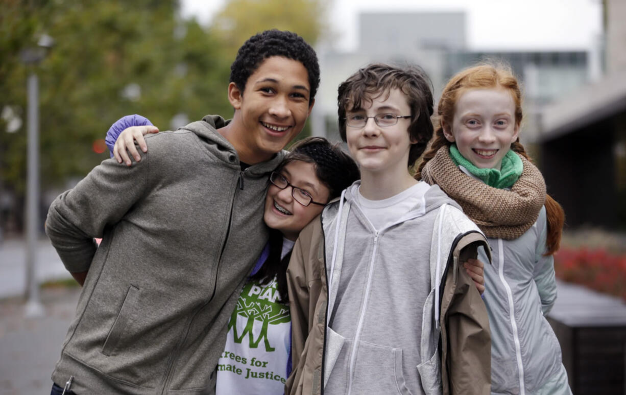 Teenage environmental activists Aji Piper, left, 15, Lara Fain, 13, Gabriel Mandell, 13, and Wren Wagenbach, 14, playfully pose for a photo after an October rally they spoke at in Seattle.