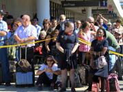 Passengers evacuated from a Los Angeles International Airport terminal where a shooting occurred Friday wait outside.