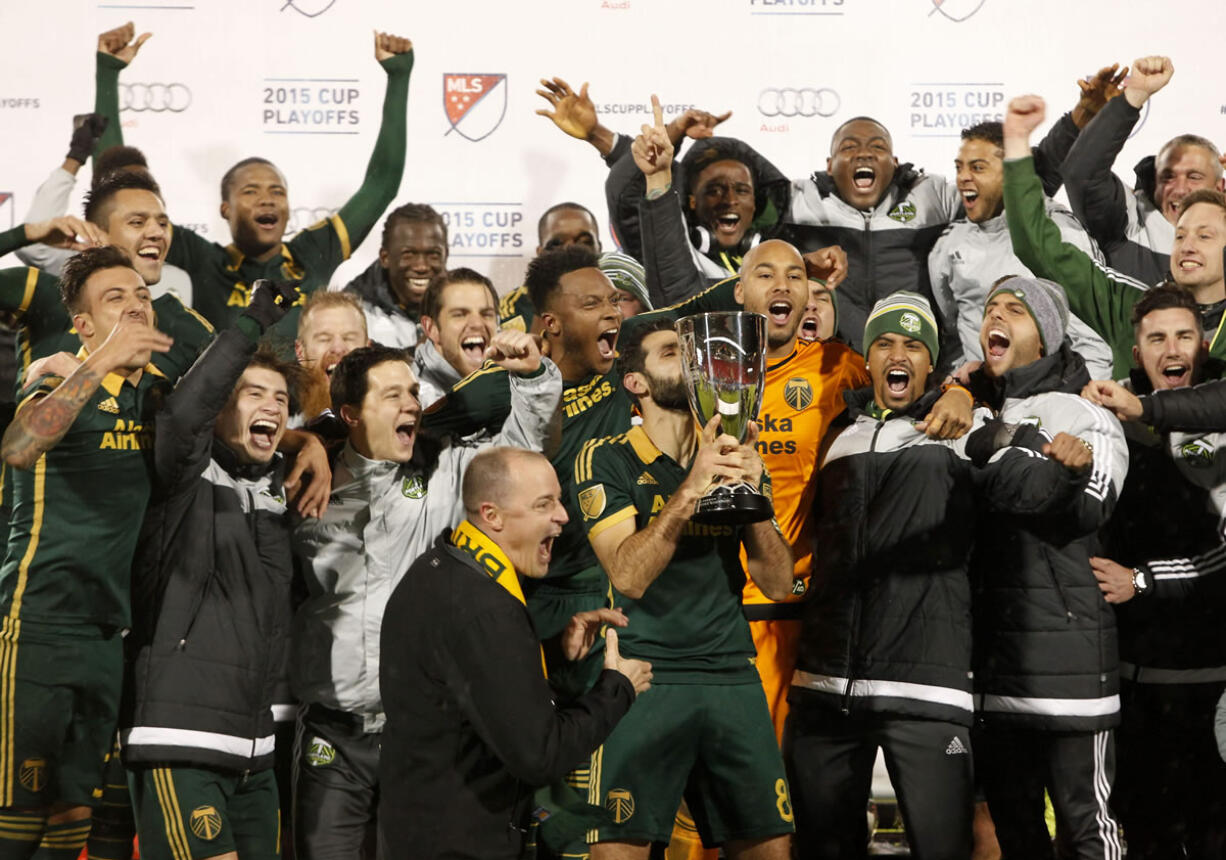 Portland Timbers midfielder Diego Valeri, middle, kisses the trophy after winning the MLS soccer western conference championship, Sunday, Nov. 29, 2015, in Frisco, Texas. The teams tie 2-2, but Portland advanced to the MLS championship on aggregate score.