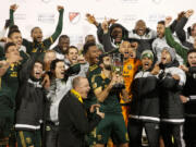 Portland Timbers midfielder Diego Valeri, middle, kisses the trophy after winning the MLS soccer western conference championship, Sunday, Nov. 29, 2015, in Frisco, Texas. The teams tie 2-2, but Portland advanced to the MLS championship on aggregate score.