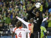 Portland Timbers goalkeeper Donovan Ricketts, right, pulls down the ball in the second half of the first game of the Western Conference semifinals in the MLS Cup soccer playoffs on Saturday, Nov. 2, 2013, in Seattle. The Timbers defeated the Sounders 2-1 in the first of two aggregate-score matches. (AP Photo/Ted S.