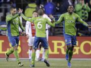 Seattle Sounders' Osvaldo Alonso (6) celebrates scoring with Clint Dempsey, left, and Shalrie Joseph against the Portland Timbers in the second half of the first game of the Western Conference semifinals in the MLS Cup soccer playoffs on Saturday, Nov. 2, 2013, in Seattle. The Timbers won 2-1 in the first of the two-game aggregate playoff series.