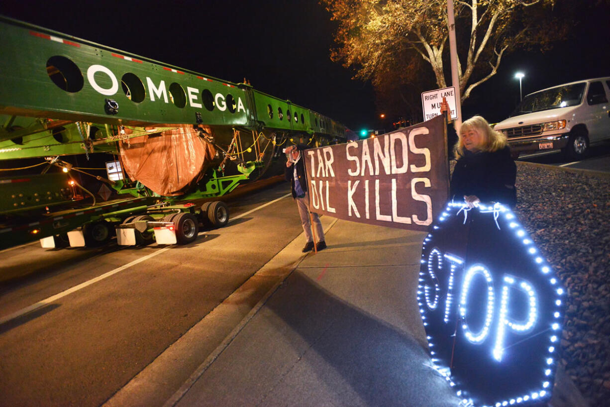 Protesters Rod Lyman and Kathy Leathers, both of Bellingham hold up signs on Highway 395 as the megaload slowly passes by in Hermiston, Ore.