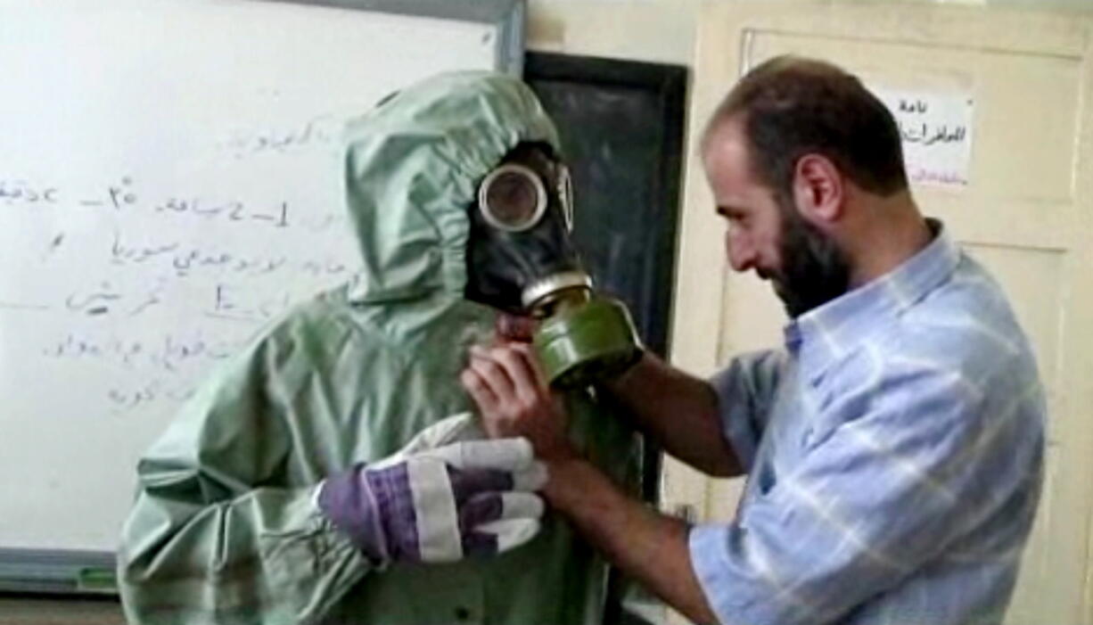 A volunteer adjusts a students gas mask and protective suit during a session on reacting to a chemical weapons attack, in Aleppo, Syria. The Islamic State group is aggressively pursuing development of chemical weapons, setting up a branch dedicated to research and experiments with the help of scientists from Iraq, Syria and elsewhere in the region, according to Iraqi and U.S. intelligence officials.