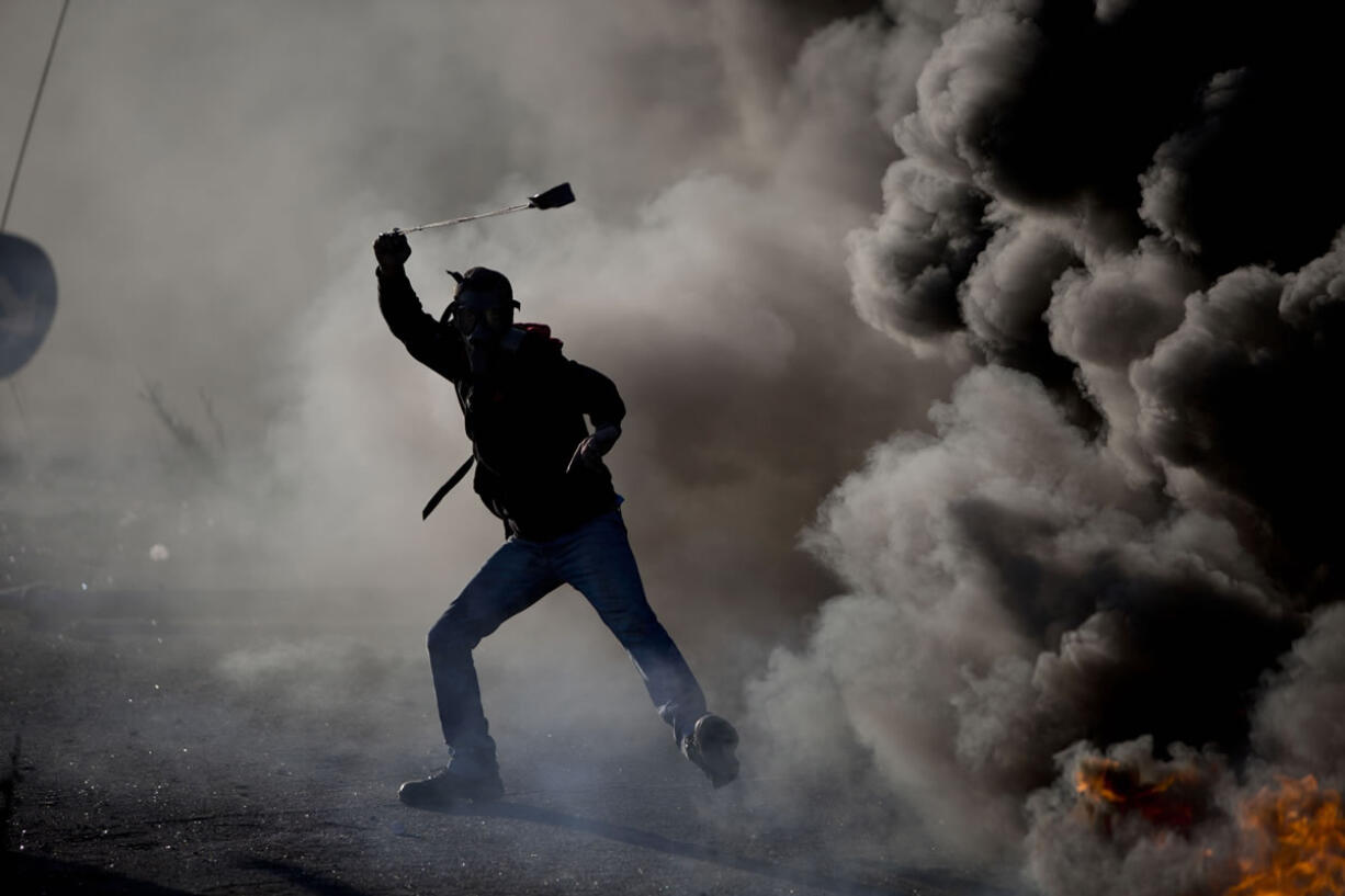 A Palestinian swings a sling during clashes with Israeli troops Friday in the West Bank city of Ramallah.