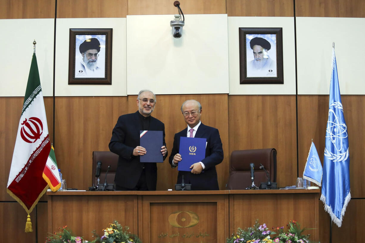 Head of Iran's Atomic Energy Organization Ali Akbar Salehi, left, and International Atomic Energy Agency Director General Yukiya Amano, pose for a photo under portraits of Iran's supreme leader, Ayatollah Ali Khamenei, left, and Iran's founder of Islamic Republic, Ayatollah Ruhollah Khomeini, right, following their meeting in Tehran, Iran, on Monday.