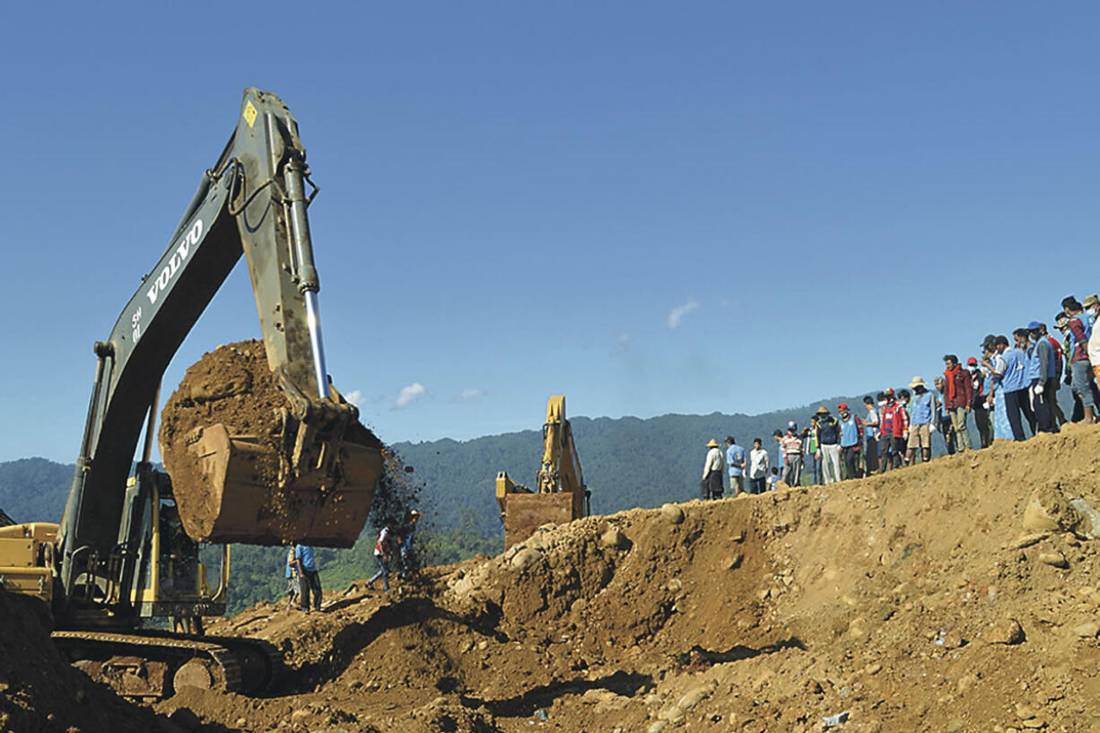 Excavators remove soil to search bodies of miners as workers and rescue members gather in Hpakant, Kachin State, Myanmar. Soldiers, police and volunteers pulled body after body from the rubble in northern Myanmar on Monday as the death toll continued to rise from a landslide near several jade mines with many more missing.