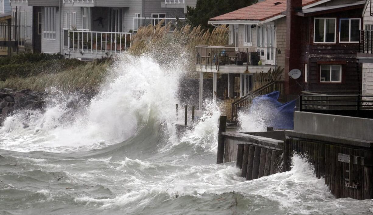 Wind-blown waves batter houses Tuesday in Seattle. Rain and high winds snarled the morning commute in the Puget Sound area and the Inland Northwest braced for severe weather that could include wind gusts to 70 mph. The National Weather Service says a Pacific storm system arriving Tuesday may include sustained winds of 45 mph that could topple trees and cause power outages.