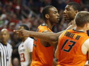 Oklahoma State's Markel Brown (22) and Phil Forte (13) hold Marcus Smart after Smart shoved a fan during their  game against Texas Tech in Lubbock, Texas, Saturday.