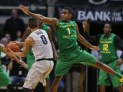 Colorado guard Askia Booker, left, looks to pass ball as Oregon guard Dominic Artis covers in the second half on Sunday at Boulder, Colo. Colorado won 100-91.