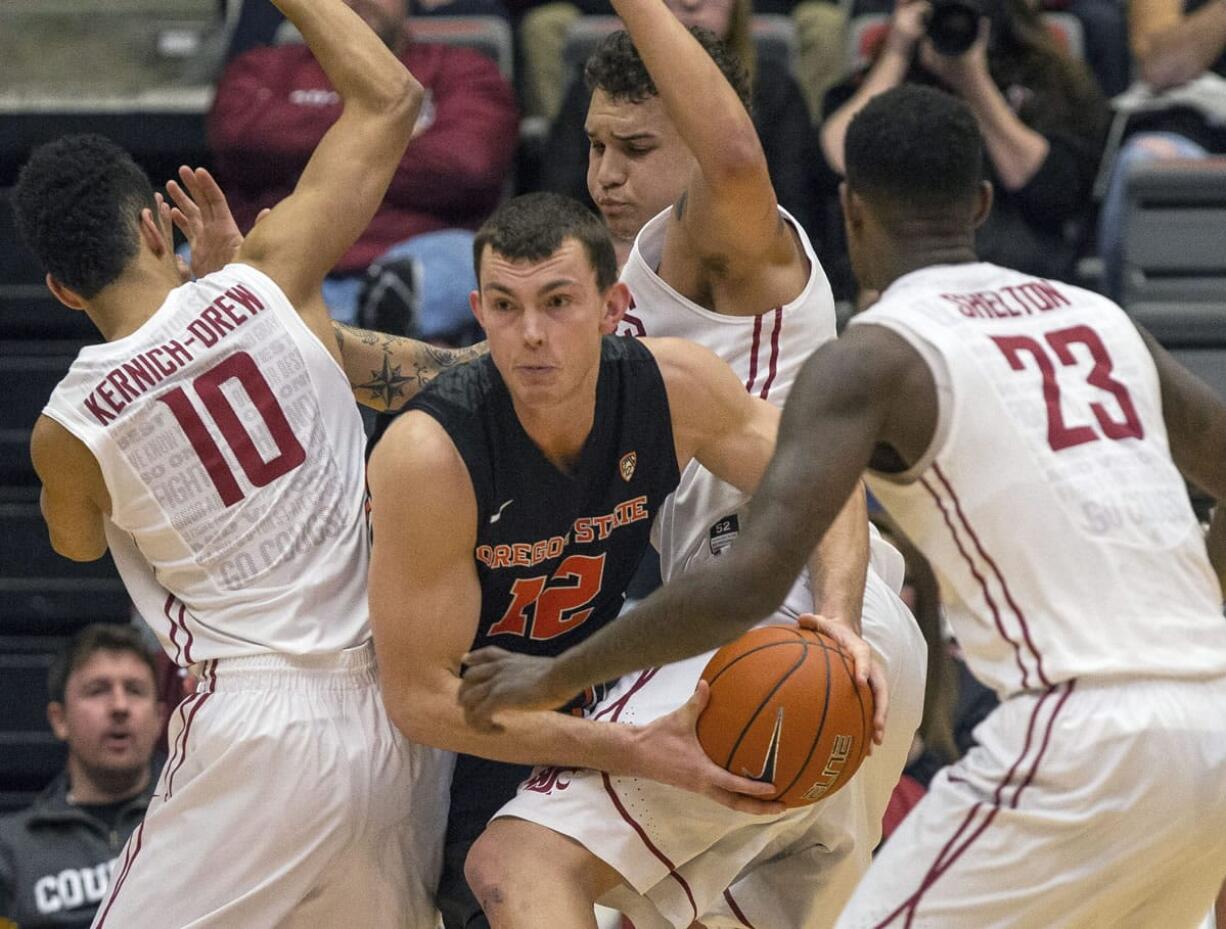 Oregon State center Angus Brandt (12) forces his way through the defense of Washington State guard Dexter Kernich-Drew (10), forward D.J.