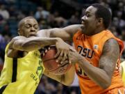 Oregon's Elgin Cook tries to strip Oregon State's Jarmal Reid of the ball in the first half of a Pac-12 tournament game Wednesday in Las Vegas.