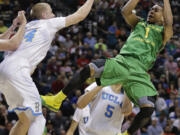 Oregon's Dominic Artis (1) puts up an off-balance shot against UCLA's Travis Wear in the second half of an NCAA Pac-12 conference tournament quarterfinal college basketball game on Thursday, March 13, 2014, in Las Vegas. UCLA won 82-63.