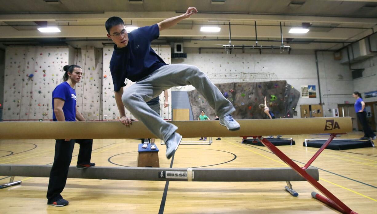 Michael Chung of Brookline, Mass., leaps over a balance beam while running an obstacle course during a Parkour training class in Brookline.