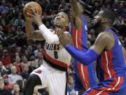 Portland Trail Blazers guard Damian Lillard, left, goes to the basket against the Detroit Pistons' Andre Drummond, right, and Brandon Jennings during the second half Monday.