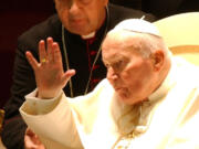 Archbishop Stanislaw Dziwisz assists a waving Pope John Paul II during a special audience Oct.