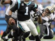 Carolina Panthers' Cam Newton (1) runs away from New Orleans Saints' Cameron Jordan (94), and Tyrunn Walker (75) in the first half of an NFL football game in Charlotte, N.C., Sunday, Dec. 22, 2013.