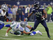 Seattle Seahawks running back Marshawn Lynch (24) breaks through a tackle-attempt by Dallas Cowboys' Sean Lee (50) as Cowboys Byron Jones, left, comes over to help on the running play in the second half of an NFL football game Sunday, Nov. 1, 2015, in Arlington, Texas.