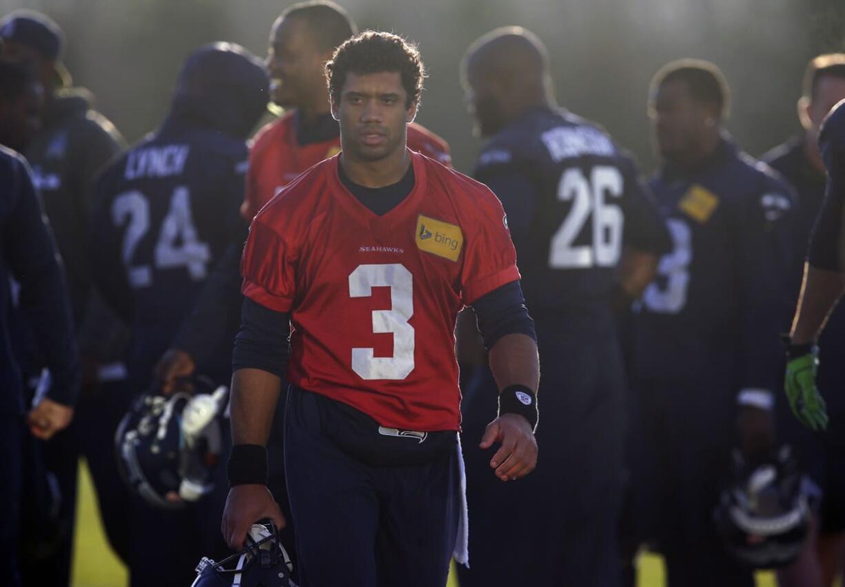 Seattle Seahawks quarterback Russell Wilson (3) walks off the practice field in hazy late afternoon sunlight at the end of practice on Wednesday in Renton.