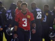 Seattle Seahawks quarterback Russell Wilson (3) walks off the practice field in hazy late afternoon sunlight at the end of practice on Wednesday in Renton.