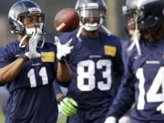 Seattle Seahawks wide receiver Percy Harvin (11) catches a ball tossed to him during warmups for Friday's practice. Looking on are wide receiver Ricardo Lockette (83) and practice squad wide receiver Arceto Clark (14). Seattle plays at home in a playoff game on Jan. 11. (AP Photo/Ted S.