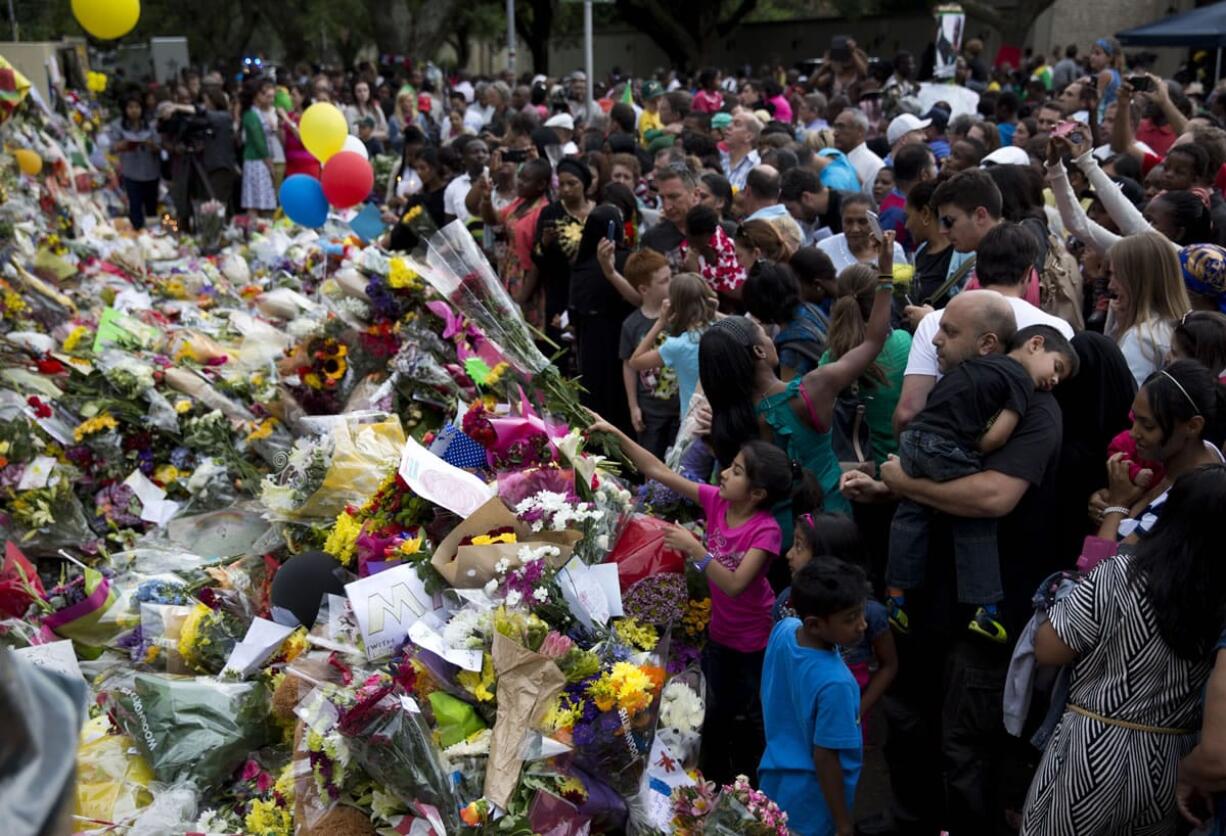 A girl lays places flowers on top of tributes Sunday outside the home of former president Nelson Mandela in Johannesburg, South Africa.