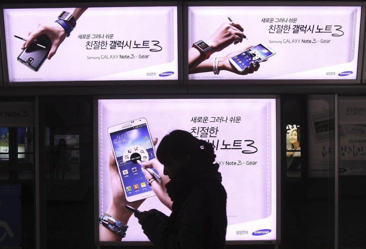 A woman walks banners advertising Samsung Electronics' Galaxy Note III at a subway station in Seoul, South Korea, Thursday, Dec. 12, 2013.