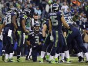 Seattle Seahawks' Russell Wilson (3) speaks to his teammates, including receivers Ricardo Lockette (83) and Jermaine Kearse (15), during huddle in the first half of the NFC championship against the San Francisco 49ers in Seattle. It's an unheralded group that have been catching passes from Wilson all season.