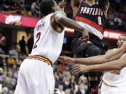 Portland Trail Blazers' Damian Lillard (0) jumps to the basket against Cleveland Cavaliers' Kyrie Irving (2) during the first quarter of an NBA basketball game Tuesday, Dec. 17, 2013, in Cleveland.