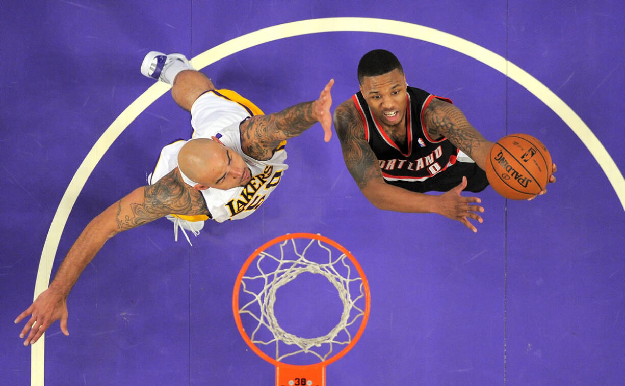 Portland Trail Blazers guard Damian Lillard, right, puts up a shot as Los Angeles Lakers center Robert Sacre defends.