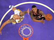 Portland Trail Blazers guard Damian Lillard, right, puts up a shot as Los Angeles Lakers center Robert Sacre defends.