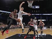 Portland's Mo Williams looks to pass around Brooklyn Nets' Mason Plumlee (1) to teammate Thomas Robinson (41) in the first half Monday at Brooklyn.