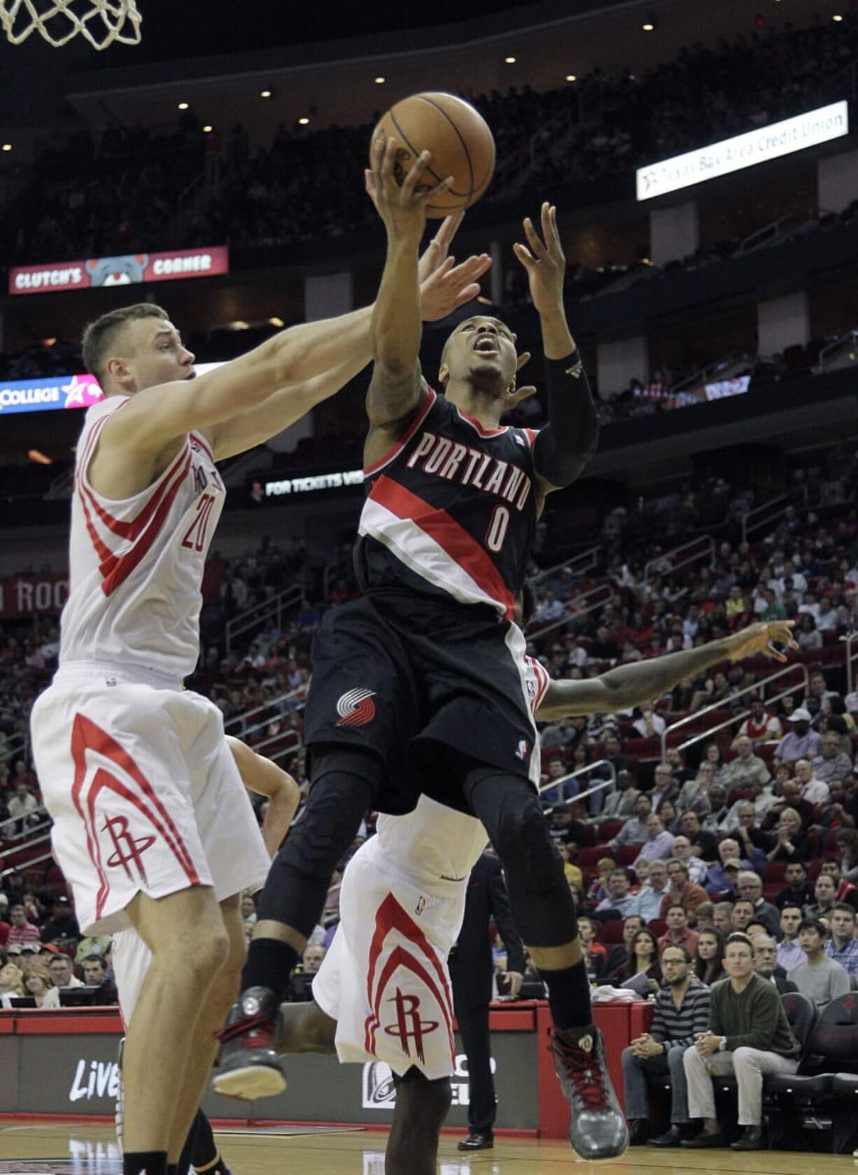 Portland Trail Blazers guard Damian Lillard (0) drives past Houston Rocket's Donatas Motiejunas (20) during the first half Monday in Houston.