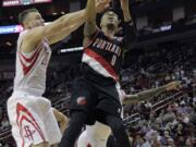 Portland Trail Blazers guard Damian Lillard (0) drives past Houston Rocket's Donatas Motiejunas (20) during the first half Monday in Houston.