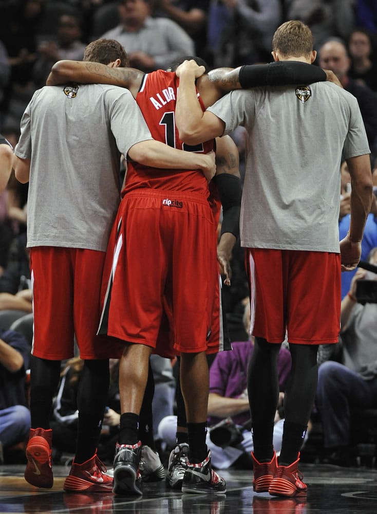 Portland Trail Blazers forward LaMarcus Aldridge, center, is helped from the court after suffering a back contusion during the second half of the Blazers' loss to the Spurs.