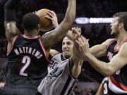 San Antonio Spurs' Manu Ginobili (20) is fouled as he drives between Portland Trail Blazers' Wesley Matthews (2) and Joel Freeland, right, during the first half Friday.