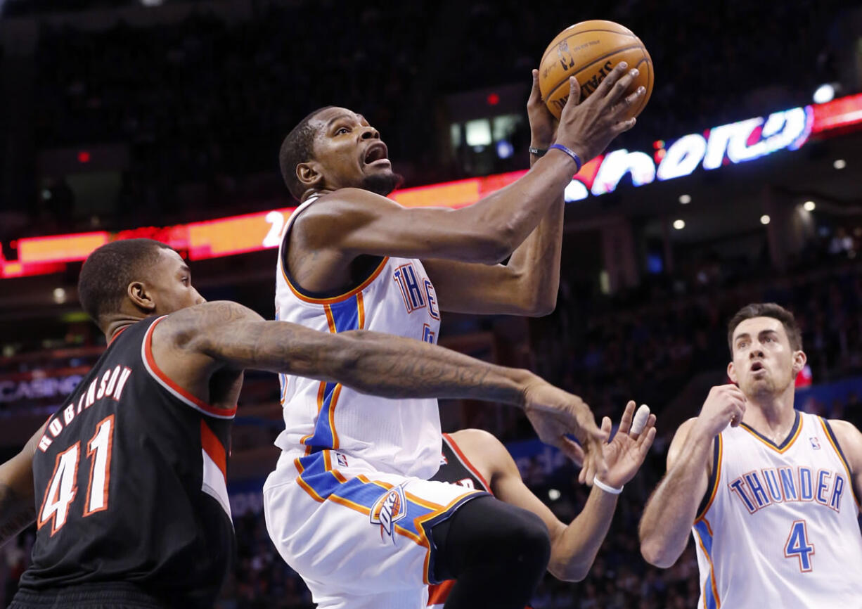 Oklahoma City Thunder forward Kevin Durant, center, shoots in front of Portland Trail Blazers forward Thomas Robinson (41) and teammate Nick Collison (4) in the third quarter of an NBA basketball game in Oklahoma City, Tuesday, Jan. 21, 2014. Oklahoma City won 105-97.