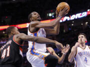 Oklahoma City Thunder forward Kevin Durant, center, shoots in front of Portland Trail Blazers forward Thomas Robinson (41) and teammate Nick Collison (4) in the third quarter of an NBA basketball game in Oklahoma City, Tuesday, Jan. 21, 2014. Oklahoma City won 105-97.