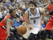 Minnesota Timberwolves guard Ricky Rubio (9) squeezes through pressure defense by Portland Trail Blazers Wesley Matthews, left, in the first quarter Saturday.