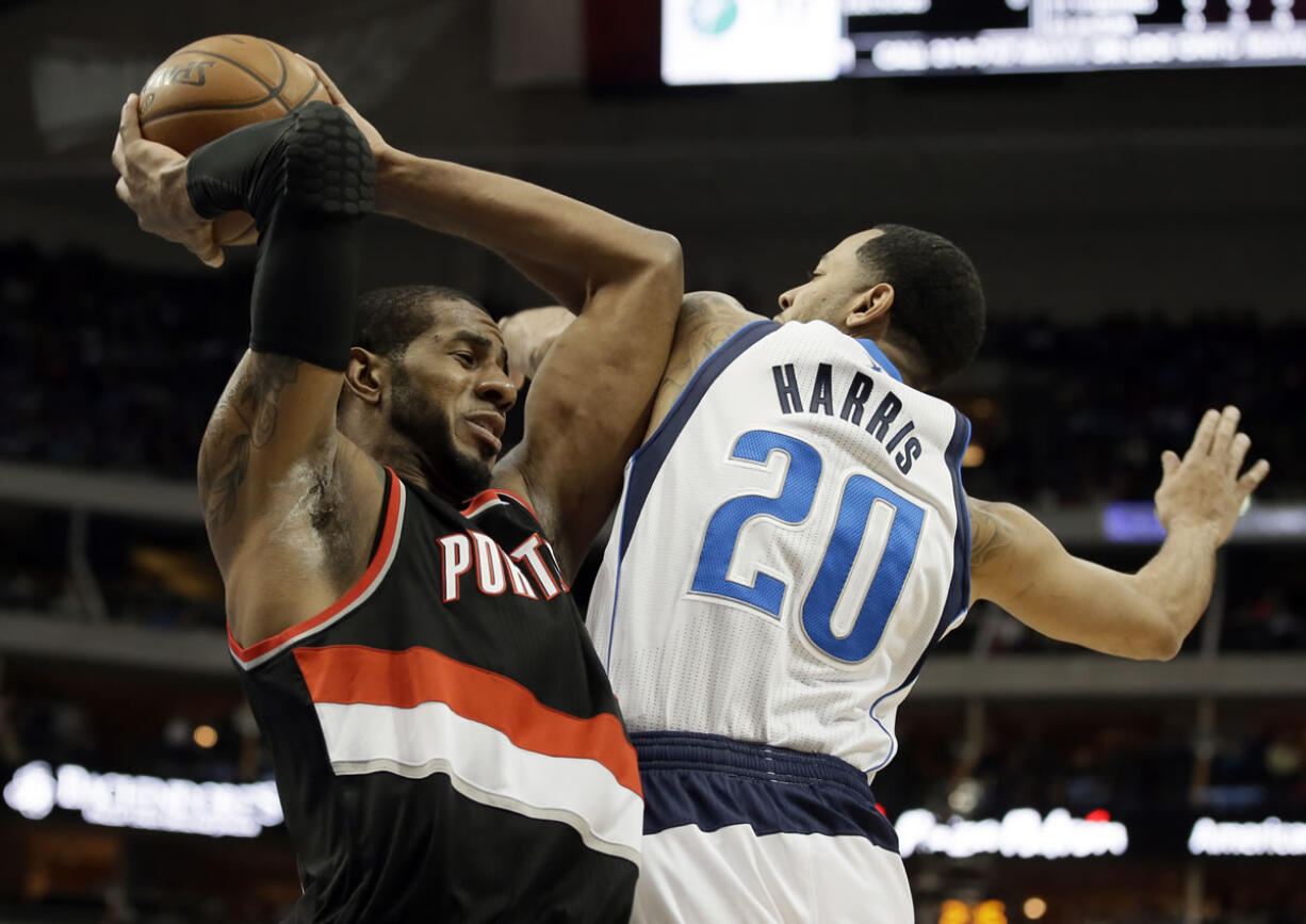 Portland Trail Blazers forward LaMarcus Aldridge, left, grabs an offensive rebound in front of Dallas Mavericks' Devin Harris (20) during the first half Saturday.